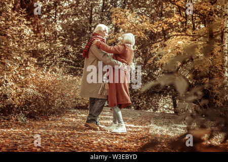 Happy senior man hugging his wife in a park. Stock Photo