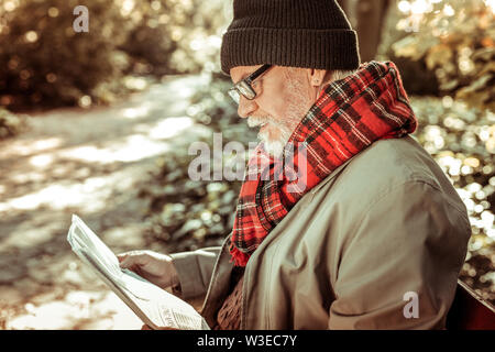 Handsome aged man reading a newspaper in the park. Stock Photo