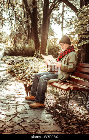 Elderly man reading his newspaper in the park. Stock Photo