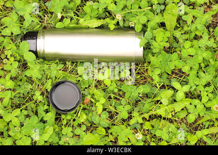 metal thermos with a lid on the green grass Stock Photo