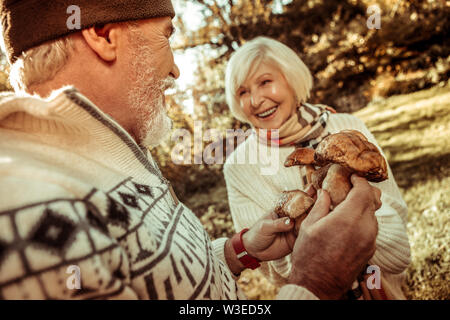 Smiling man holding mushrooms and talking to his wife. Stock Photo
