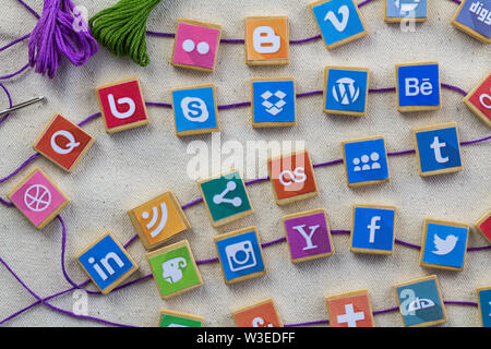 QUEENSTOWN, SOUTH AFRICA - 7 JULY 2019 -Social media background with social media logos on wooden game blocks joined with embroidery thread and needle Stock Photo