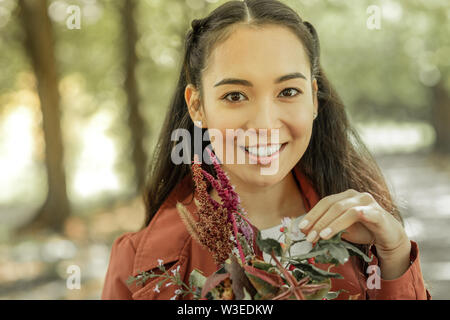Beaming dark-haired lady showing bright smile while carrying Stock Photo