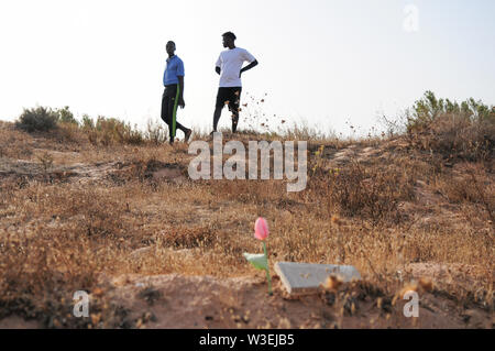 Zarzis, Tunisia. 14th July, 2019. Mamadou Kamarra (l), and Ousmane Koulibali, both from Mali, stand at the 'Cemetery of the Unknown'. Kamarra and Koulibali are two survivors of a recent shipwreck off the Tunisian coast in which 83 people died. On the beaches of the southern Tunisian town of Zarzis, near the holiday island of Djerba, the bodies of drowned migrants are washed up again and again. (to dpa: The Bay of the Nameless Dead) Credit: Simon Kremer/dpa/Alamy Live News Stock Photo