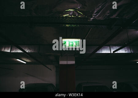 Close up of an exit this way sign inside an underground parking place Stock Photo