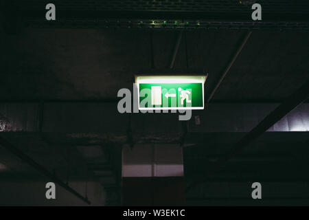 Close up of an exit this way sign inside an underground parking place Stock Photo