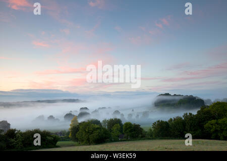 A layer of mist in the Nadder Valley at Sutton Mandeville in Wiltshire. Stock Photo