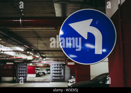 Mandatory turn left road signal inside an underground parking Stock Photo