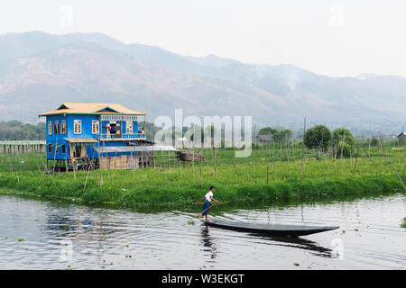 Maing Thauk, Myanmar - April 2019: traditional Burmese floating house reflecting in water of Inle lake.