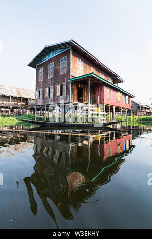 Maing Thauk, Myanmar - April 2019: traditional Burmese floating house reflecting in water of Inle lake.