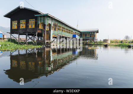 Maing Thauk, Myanmar - April 2019: traditional Burmese floating school reflecting in water of Inle lake.