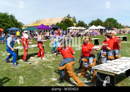 Two teams in fancy dress in field with audience watching, throwing custard pies at each other  during the yearly World Custard Pie Championship 2019. Stock Photo