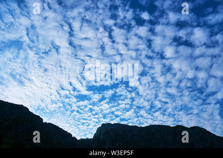 Altocumulus floccus clouds, blue morning sky, and a mountain ridge silhouette. Location: Trascau mountains (part of Carpathians), near Rimetea village Stock Photo