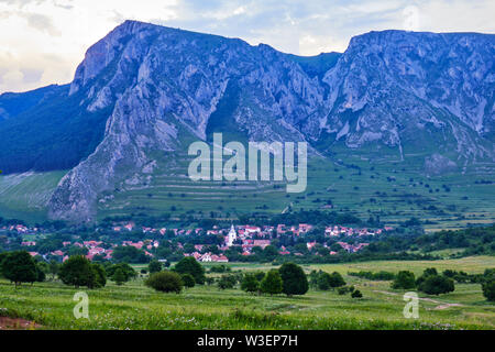 Rimetea village, Alba county, Romania, at evening, with imposing Coltii Trascaului and Piatra Secuiului (part of Trascau mountains in Carpathians) in Stock Photo