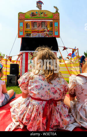 Broadstairs Dickens festival. View over the shoulder of young children in Victorian era Dickensian costume watching a Punch and Judy show outdoors. Stock Photo