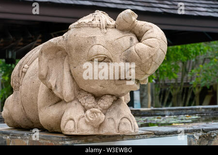 little funny elephant, sculpture, sitting under an umbrella.lies. Stock Photo