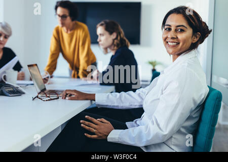 Smiling business woman sitting in conference room during presentation. Young woman sitting in board room. Stock Photo