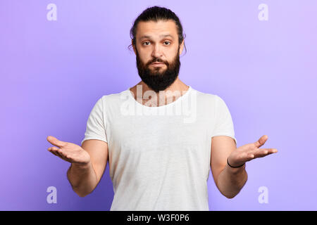 serious man standing with raised hands, explaing something, talking , gesturing and looking at camera isolated on a blue background Stock Photo