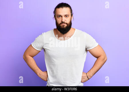 Serious dissatisfied strong confident man with hands on his hips posing against blue background.close up photo.people Stock Photo