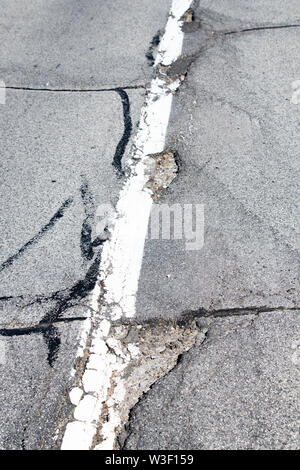 Potholes in the asphalt on a street in Speculator, NY USA, a hazard to motorists. Stock Photo