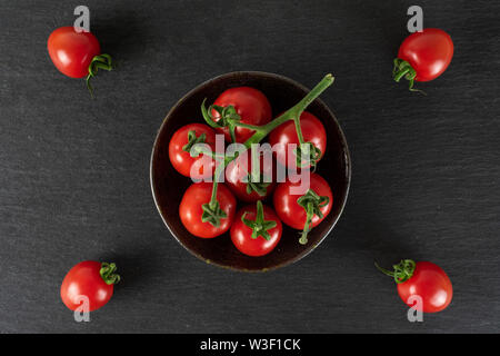 Lot of whole fresh red tomato cherry on a ceramic grey plate flatlay on grey stone Stock Photo