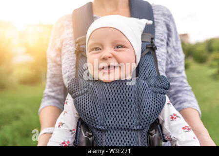 Young mother and her baby girl in a baby carrier. Stock Photo