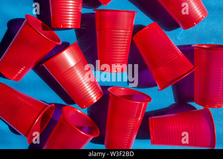 Red plastic cups on a blue background. Composition from empty plastic glasses. Many disposable beverage containers. View from above Stock Photo