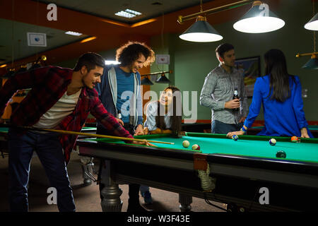 Young people play billiards. A group of young people playing fun billiards. Stock Photo