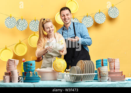 happy young couple washing in the kitchen with yellow wall.close up photo. Stock Photo