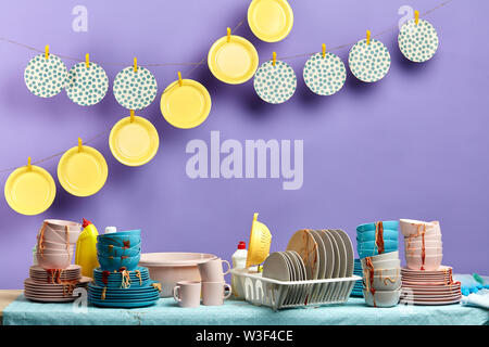 pile of dirty used dishes waiting for wash. clean tables hanging on the clothespins. blue background. studio shot Stock Photo