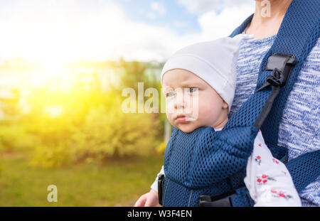 Young mother and her baby girl in a baby carrier. Stock Photo