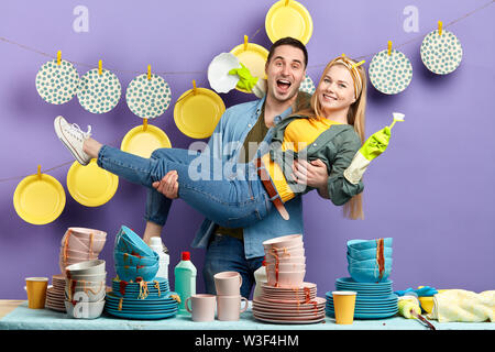 crazy man and woman get pleasure from washing dishes in the kitchen Stock Photo