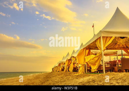 Luxurious tents at desert beach camp, Inland Sea, Khor al Udaid in Persian Gulf, southern Qatar. Scenic sunset sky in Middle East, Arabian Peninsula Stock Photo