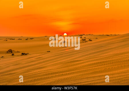 Red and orange colors of sunset sky over sand dunes at Inland Sea. Desert landscape near Qatar and Saudi Arabia. Khor Al Udeid, Persian Gulf, Middle Stock Photo