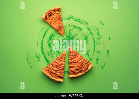 Three pieces of apple pie and traces of grease on the green paper background from the whole pie. Above view of portions of a traditional American pie. Stock Photo