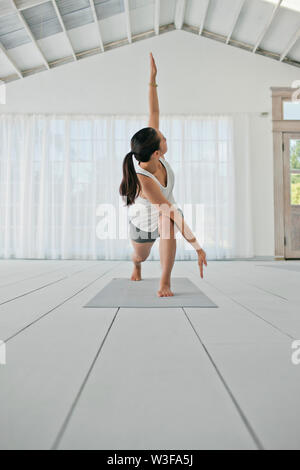 Happy young woman stretching her arms and legs while practicing yoga. Stock Photo
