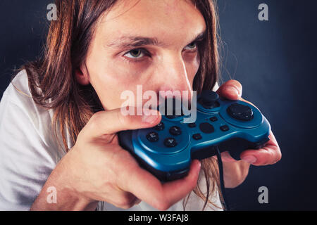 Lifestyle of young people. Student man spending time on playing games videogames console playstation. Long haired guy focus on gaming. Stock Photo