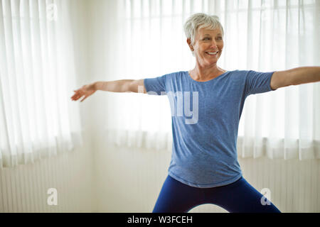Happy Mature Woman practicing yoga at home. Stock Photo