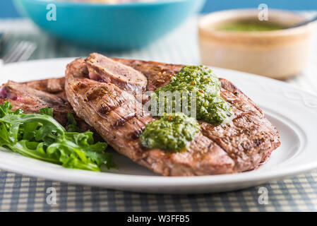 Chargrilled British Lamb leg steaks with chimichurri sauce and potato salad. Close up with the sauce. Stock Photo