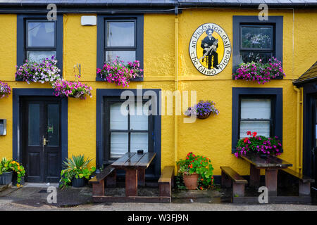 The Blind Piper, a yellow typical Irish pub in County Kerry .  Outdoor seating area before opening. Caherdaniel, Ireland Stock Photo