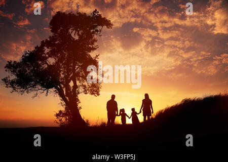 Happy family silhouette standing on against sunset time. Stock Photo