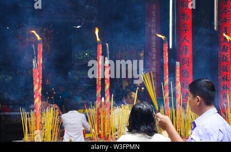 HO CHI MINH CITY, VIETNAM - JANUARY 5. 2015: Buddhist believers light incense sticks at shrine in chinese buddhist temple Stock Photo