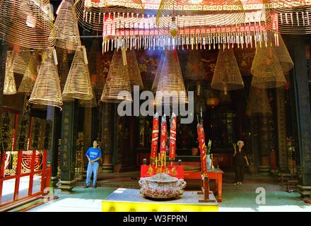 HO CHI MINH CITY, VIETNAM - JANUARY 5. 2015: Inside Buddhist temple with hanging spiral incense coils and burning sticks with massive smoke Stock Photo