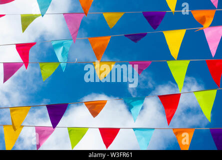 Colourful bunting flags against blue sky in Spanish village during local fiesta. Stock Photo