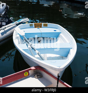 A light blue row boat is tied up to other boats that are tied up to a dock in Maine. Stock Photo