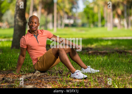 Attractive young African American male model sitting in the park glancing over his shoulder Stock Photo