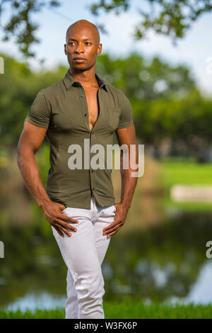 Photo of a handsome man posing with hands in pockets at a park setting Stock Photo