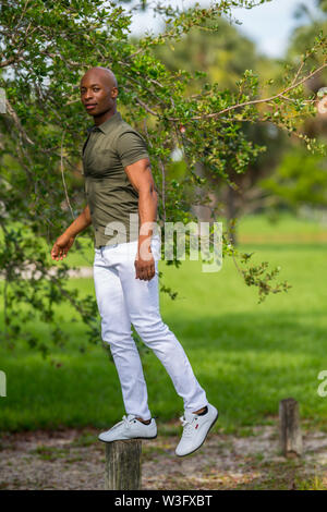Image of a handsome young African American man balancing on a fitness post in the park Stock Photo