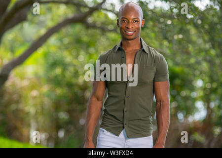Handsome man posing in stylish clothing at a park scene in summer Stock Photo