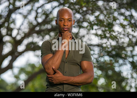 Handsome young African American man posing with hand on chin in a nature scene Stock Photo